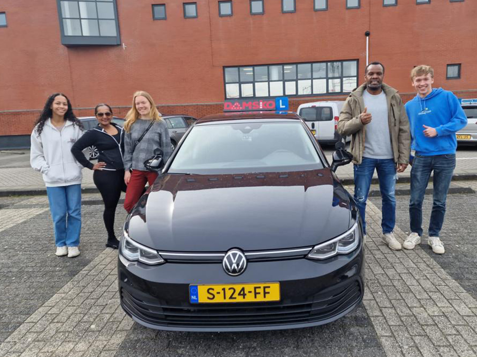 Het team van Rijschool Damsko Amsterdam bij een lesauto